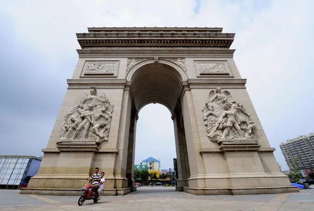 A motorcyclist rides past a 10-metre-high miniature replica of the Arc de Triomphe monument in Paris, in Jiangyan, Jiangsu province, August 10, 2014. (Photo by Reuters/Stringer)