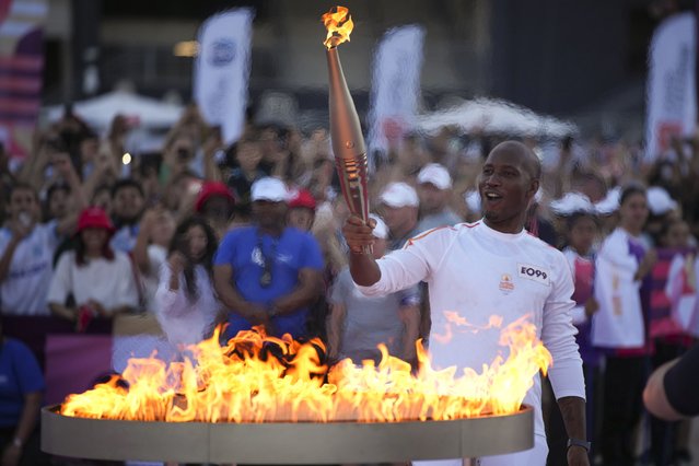 Torchbearer Didier Drogba of France holds the torch to light the cauldron at the Velodrome stadium in Marseille, southern France, Thursday, May 9, 2024. Torchbearers are to carry the Olympic flame through the streets of France's southern port city of Marseille, one day after it arrived on a majestic three-mast ship for the welcoming ceremony. (Photo by Daniel Cole/AP Photo)