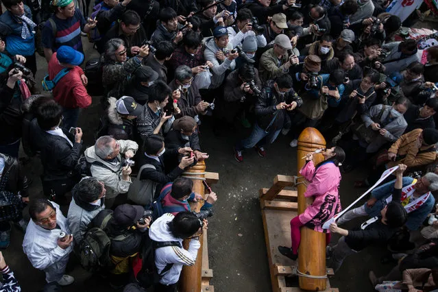 A woman poses for photographers as she sits on a large wooden phallic sculpture during Kanamara Matsuri (Festival of the Steel Phallus) on April 6, 2014 in Kawasaki, Japan. The Kanamara Festival is held annually on the first Sunday of April. The pen*s is the central theme of the festival, focused at the local pen*s-venerating shrine which was once frequented by prostitutes who came to pray for business prosperity and protection against sexually transmitted diseases. (Photo by Chris McGrath/Getty Images)