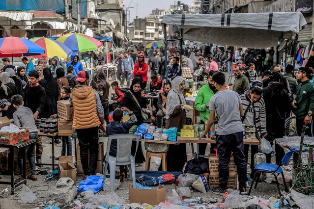 People shop from vendors in an open-air market amidst destruction in Gaza City on March 27, 2024 amid the ongoing conflict in the Gaza Strip between Israel and the Palestinian militant group Hamas. (Photo by AFP Photo)