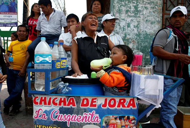 A street vendor sells corn juice with her child while awaiting Peru's presidential candidate Pedro Pablo Kuczynski's rally in Puente Piedra, Lima, Peru, May 3, 2016. (Photo by Mariana Bazo/Reuters)