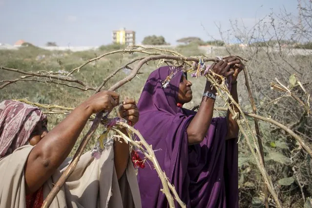 Somali women who fled drought-stricken areas start to build shelters at a makeshift camp on the outskirts of the capital Mogadishu, Somalia Friday, February 4, 2022. Thousands of desperate families have fled a severe drought across large parts of Somalia, seeking food and water in camps for displaced people outside the capital. (Photo by Farah Abdi Warsameh/AP Photo)