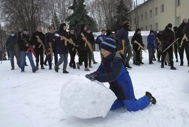 A boy makes snow ball while local residents in background, take part in military defense training, in Kyiv, Ukraine, Sunday, January 30, 2022. Russia's foreign minister claims that NATO wants to pull Ukraine into the alliance, amid escalating tensions over NATO expansion and fears that Russia is preparing to invade Ukraine. In comments on state television Sunday, Foreign Minister Sergey Lavrov also challenged NATO's claim to be a purely defensive structure. (Photo by Efrem Lukatsky/AP Photo)