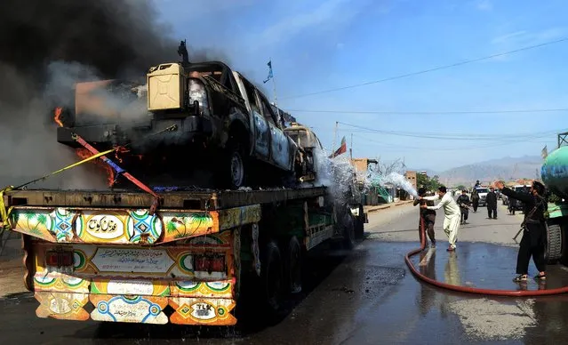 Pakistani firefighters try to extinguish a NATO truck caught on fire in the Pakistani tribal area of Jamrud near Peshawar, Pakistan, Monday, May, 5, 2014. A local Pakistani government official says militants have attacked a NATO supply convoy en route to Afghanistan, killing two drivers. (Photo by Mohammad Sajjad/AP Photo)