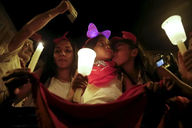 Revellers hold up red scarves and candles during the closing ceremony of the San Fermin festival in Pamplona, northern Spain, early July 15, 2015. Thousands of people gathered in front of the city's town hall to sing the traditional farewell song “Pobre de mi” (Poor me). The song is sung by revellers to show their sadness at the end of the festival. (Photo by Susana Vera/Reuters)