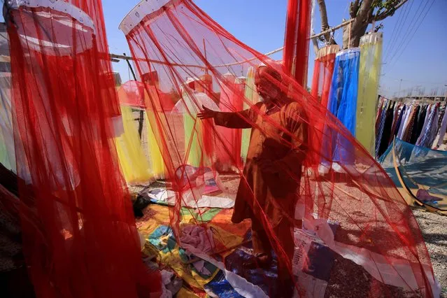 A man waits for customers as he sells Mosquito prevention nets at a road side in Peshawar, Pakistan, 16 March 2022. Every year hundreds of people suffer from Dengue fever caused by the biting of Mosquitos in Pakistan. (Photo by Bilawal Arbab/EPA/EFE)