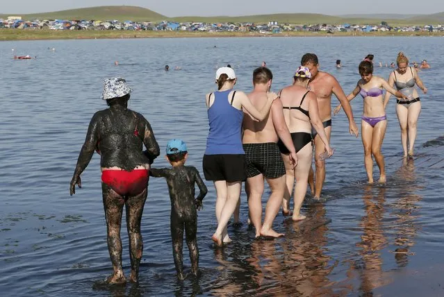 A woman and a child covered with mineral-rich black mud go for a swim in the waters of Tus lake in Khakassia region, southwest of the Siberian city of Krasnoyarsk, Russia, July 18, 2015. (Photo by Ilya Naymushin/Reuters)