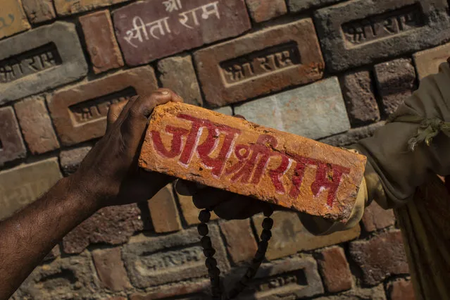 In this Sunday, November 25, 2018 photo, a man holds a brick reading “Jai Shree Ram” (Victory to Lord Ram) as bricks of the old Babri Mosque are piled up in Ayodhya, in the central Indian state of Uttar Pradesh. State-run broadcaster on Saturday, Nov. 9, 2019, said top court rules for disputed temple-mosque land for Hindus with alternate land to Muslims. Authorities increased security in Ayodhya, 550 kilometers (350 miles) east of New Delhi, and deployed more than 5,000 paramilitary forces to prevent any attacks by Hindu activists on Muslims, who comprise 6% of the town's more than 55,500 people. (Photo by Bernat Armangue/AP Photo/File)