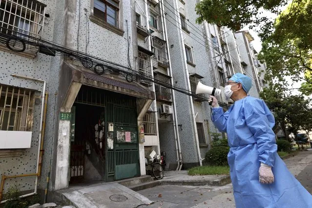 In this photo released by China's Xinhua News Agency, a volunteer uses a megaphone to talk to residents at an apartment building in Shanghai, China, Tuesday, April 12, 2022. Shanghai has released more than 6,000 more people from medical observation amid a COVID-19 outbreak, the government said Wednesday, but moves to further ease the lockdown on China's largest city appeared to have stalled. (Photo by Chen Jianli/Xinhua via AP Photo)