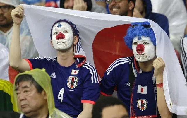 Japanese fans protect themselves from the rain with a Japanese flag during the group C World Cup soccer match between Ivory Coast and Japan at the Arena Pernambuco in Recife, Brazil, Saturday, June 14, 2014. (Photo by Petr David Josek/AP Photo)