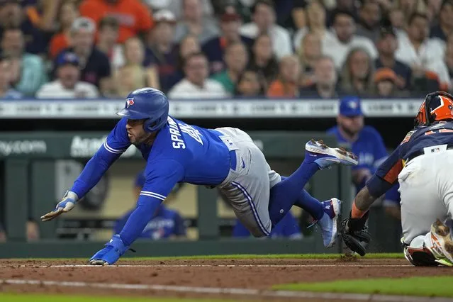 Toronto Blue Jays' George Springer (4) avoids the tag of Houston Astros catcher Martin Maldonado as he scores during the fourth inning of a baseball game Sunday, April 24, 2022, in Houston. (Photo by David J. Phillip/AP Photo)