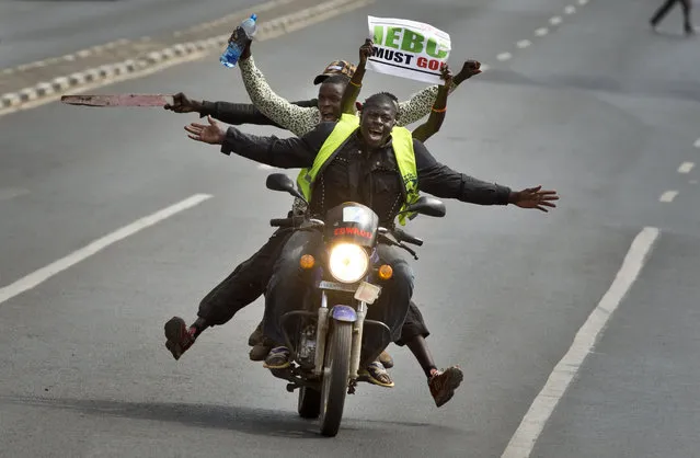 A motorcycle carrying protesters holding a placard using the acronym of the national electoral commission, drives ahead of demonstrators on foot calling for the disbandment of the commission over allegations of bias and corruption, in downtown Nairobi, Kenya Monday, June 6, 2016. (Photo by Ben Curtis/AP Photo)