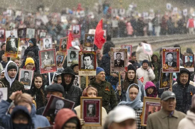 People carry portraits of relatives who fought in World War II, during the Immortal Regiment march in Ulan-Ude, the regional capital of Buryatia, a region near the Russia-Mongolia border, Russia, Monday, May 9, 2022, marking the 77th anniversary of the end of World War II. (Photo by AP Photo/Stringer)