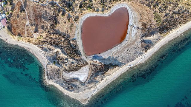 An aerial view of the Pink Lake known as 'Kalpli Gol' (hearth-shaped lake) located near the village of Dalyan in the Ezine district of Canakkale, Turkiye on August 18, 2024. The Lake named pink because its water turns tile-colored and pink at certain times of the year. A phytoplankton named 'Dunaliella Salina' lives in the lake gives its unique pink color of the lake. (Photo by Deniz Kalayci/Anadolu via Getty Images)