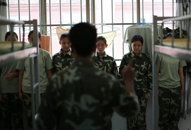 An instructor who is an ex-soldier talks to female students in their dormitory at the Qide Education Center in Beijing June 10, 2014. The Qide Education Center is a military-style boot camp which offers treatment for internet addiction. (Photo by Kim Kyung-Hoon/Reuters)