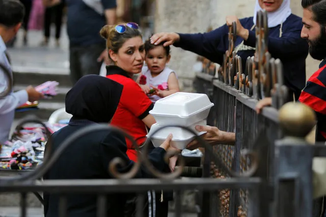A woman receives food given out as Iftar meals by members of Saaed group for the poor and internally displaced Syrians during the month of Ramadan in Damascus, Syria June 18, 2016. (Photo by Omar Sanadiki/Reuters)