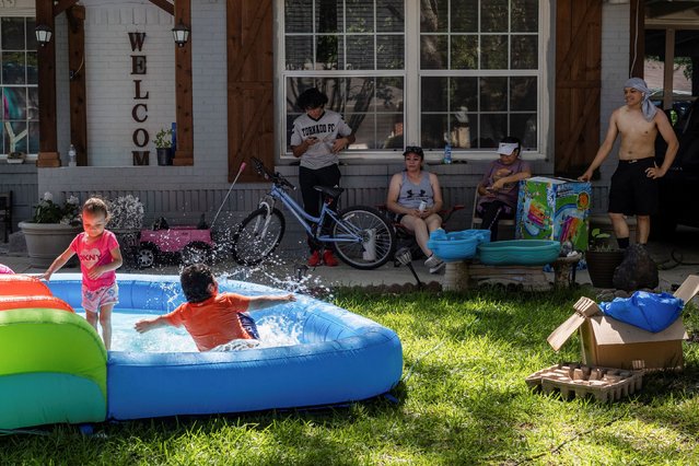 Neighbors Samuel Hernandez, Maria Hernandez, Luisa Ortega and Issac Montelongo sit outside as they watch the kids play in water during a heatwave with expected temperatures of 102 F (39 C) in Dallas, Texas, U.S. June 12, 2022. Though the heat wave caused electricity use in Texas to reach an all time high, the power grid remained largely stable without major issues. (Photo by Shelby Tauber/Reuters)
