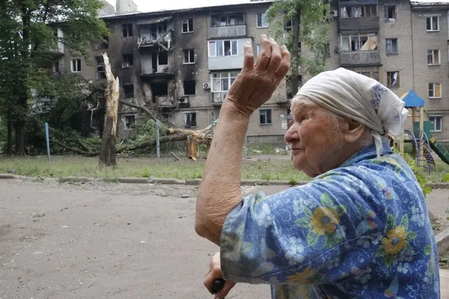 A woman gestures near an apartment building damaged during shelling in Donetsk, in territory under the government of the Donetsk People's Republic, eastern Ukraine, Wednesday, June 22, 2022. (Photo by Alexei Alexandrov/AP Photo)