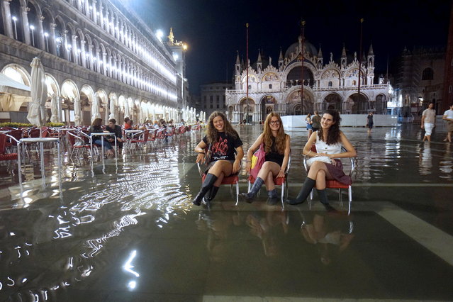 People sit in St Mark's square, flooded by water reaching up to 1 meter, in Venice, Italy, in the night between 02 and 03 August 2023. (Photo by Andrea Merola/EPA)