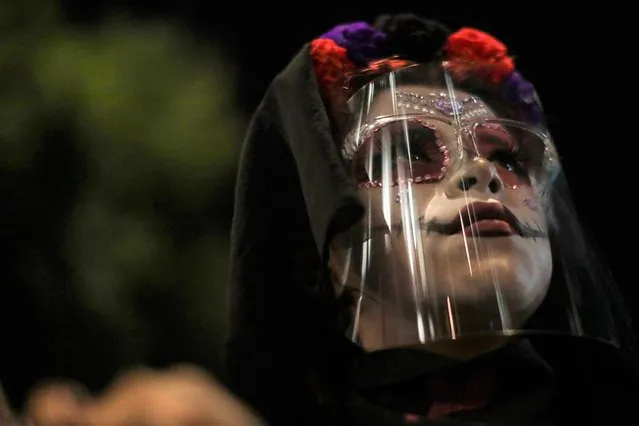 A woman painted as Catrina wears a face shield during the “March of the Catrinas” to protest against femicide and violence against women in Mexico City, Mexico on November 1, 2021. (Photo by Raquel Cunha/Reuters)