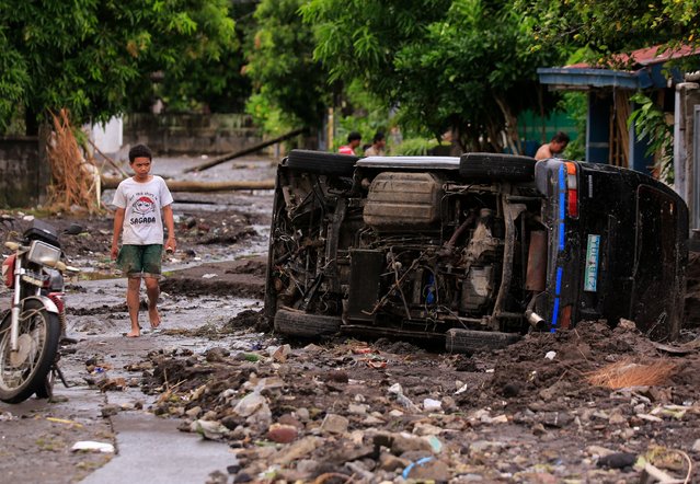 A resident looks at a destroyed car overturned by flood waters due to heavy rains brought about by Tropical Storm Trami in Oas town, Albay province South of Manila on October 23, 2024. (Photo by Charism Sayat/AFP Photo)