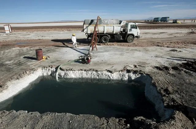 A worker stands nearby as brine is extracted from a pool at Uyuni salt lake, Bolivia, August 15, 2015. Uyuni salt lake holds the world's largest reserve of lithium. Bolivia's Evo Morales' government signed a contract with German company K-utec salt technologies to complete a lithium carbonate plant according to local media. (Photo by David Mercado/Reuters)