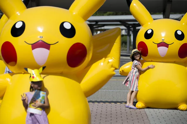 Girls pose for photographs with balloons of Pikachu, a character from Pokemon series game titles, during the Pikachu Outbreak event hosted by The Pokemon Co. on August 9, 2017 in Yokohama, Kanagawa, Japan. A total of 1, 500 Pikachus appear at the city's landmarks in the Minato Mirai area aiming to attract visitors and tourists to the city. The event will be held through until August 15. (Photo by Tomohiro Ohsumi/Getty Images)
