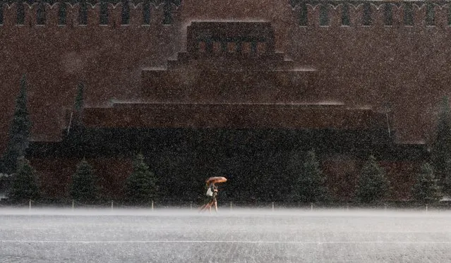 People walk by the Lenin mausoleum during heavy rain in the Red Square in Moscow, Russia on July 25, 2022. (Photo by Maxim Shemetov/Reuters)