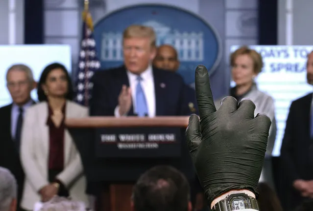 A reporter wearing a latex glove raises his hand to ask U.S. President Donald Trump a question during Coronavirus briefing at the White House on March 16, 2020 in Washington, DC. The United States has surpassed 3,000 confirmed cases of the coronavirus, and the death toll climbed to at least 61, with 25 of the deaths associated with the Life Care Center in Kirkland, Washington. (Photo by Win McNamee/Getty Images)