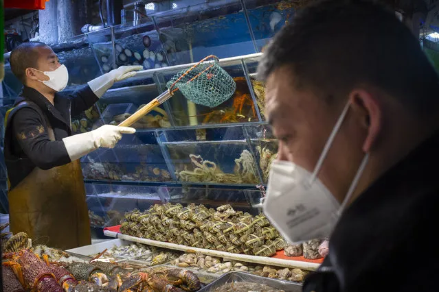 A customer wears a face mask as he shops for seafood at a market in Beijing, Saturday, March 14, 2020. The United States declared a state of emergency Friday as many European countries went on a war footing amid mounting deaths as the world mobilized to fight the widening coronavirus pandemic. For most people, the new coronavirus causes only mild or moderate symptoms, such as fever and cough. For some, especially older adults and people with existing health problems, it can cause more severe illness, including pneumonia. (Photo by Mark Schiefelbein/AP Photo)