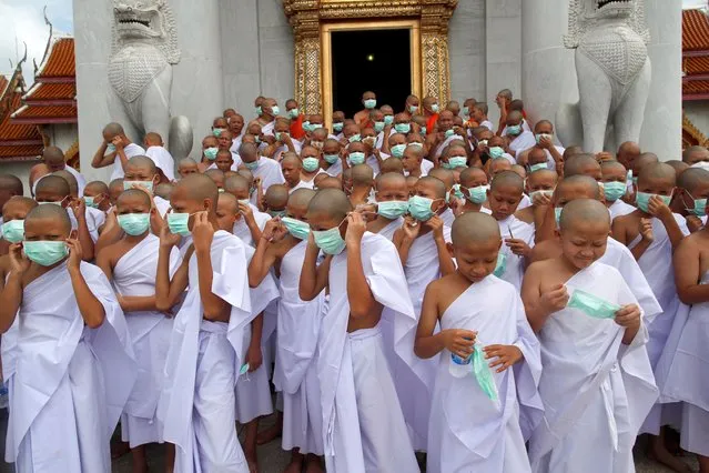Newly ordained hill tribe Buddhist novice monks put on face masks during the annual 57th Buddhist monk ordination ceremony for hill tribe men at Wat Benchamabophit Dusitwanaram, also known as the Marble Temple in Bangkok, Thailand, 03 July 2022. A total of 174 hill tribe men including young boys from northern provinces were to be ordained as Buddhist monks and novices in the annual mass ordination ceremony to mark the three-month Buddhist Lent which this year begins on 14 July. For the duration of the Buddhist Lent, monks remain in one location, typically in a monastery or on temple grounds, where they engage in meditation and prayer, while laypeople choose to observe Lent by giving up meat, alcohol, and perform other ascetic practices. In Thailand, a Buddhist man is expected to become a monk during some period of his life. (Photo by Rungroj Yongrit/EPA/EFE)