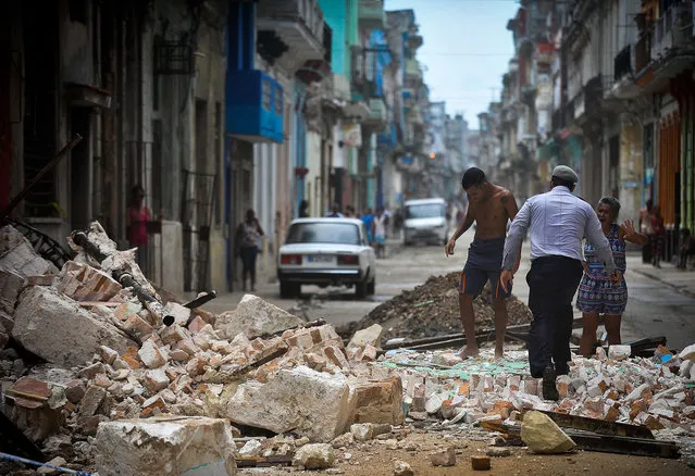 Cubans wade through the rubble from a collapsed building in Havana, on September 9, 2017. Irma's blast through the Cuban coastline weakened the storm to a Category Three, but it is still packing 125 mile-an-hour winds (205 kilometer per hour) and was expected to regain power before hitting the Florida Keys early Sunday, US forecasters said. The Cuban government extended its maximum state of alert to three additional provinces, including Havana, amid fears of flooding in low-lying areas. (Photo by Yamil Lage/AFP Photo)
