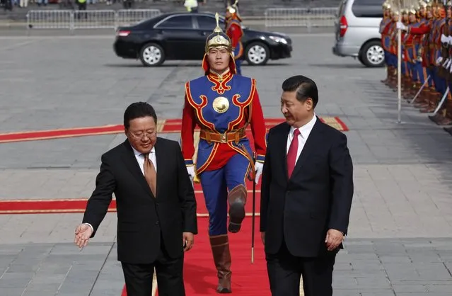 Mongolia's President Tsakhia Elbegdorj (L) gestures to his Chinese counterpart Xi Jinping (R) as they inspect an honour guard during a welcoming ceremony, outside the national parliament building at Sukhbaatar square in Ulan Bator August 21, 2014. Xi arrived in Mongolia on Thursday for a two-day visit designed to deepen economic ties between the neighbors, with Mongolia desperate to kick-start its struggling economy with fresh investment. (Photo by B. Rentsendorj/Reuters)