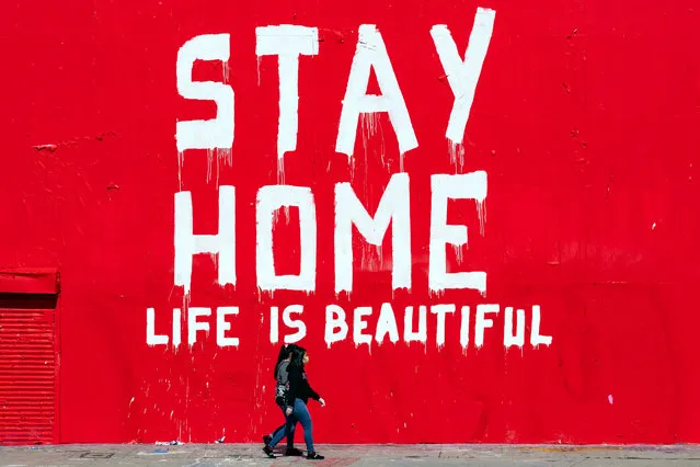 Two women wearing face masks walk past a mural reading “Stay Home Life Is Beautiful” amid the coronavirus pandemic in Los Angeles, California, USA, 07 April 2020. Countries around the world are taking increased measures to stem the spread of the SARS-CoV-2 coronavirus which causes the Covid-19 disease. (Photo by Etienne Laurent/EPA/EFE)