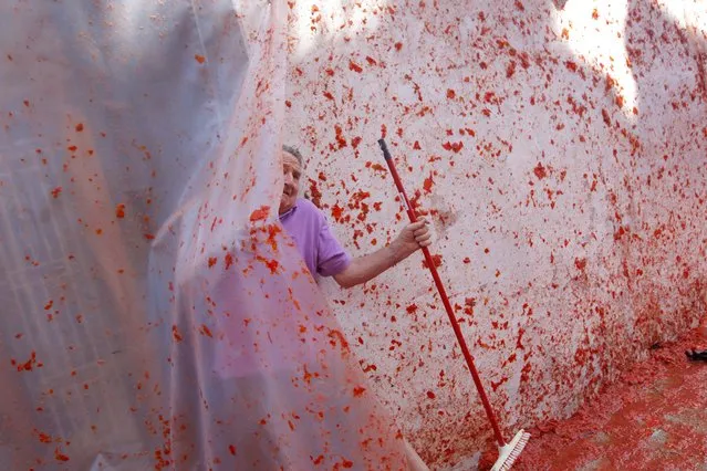 A man attempts to clean the remains of tomatoes from outside his house after the annual “Tomatina” tomato fight fiesta in the village of Bunol, 50 kilometers outside Valencia, Spain, Wednesday, August 27, 2014. (Photo by Alberto Saiz/AP Photo)