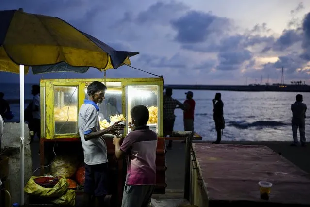 A vendor sells snacks at the Galle sea face promenade near the ongoing protest site in Colombo, Sri Lanka, Friday, July 29, 2022. (Photo by Eranga Jayawardena/AP Photo)