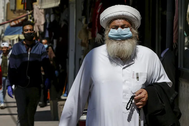 A man wears a protective face mask as he walks along the main market in downtown after the government eased the restrictions on movement aimed at containing the spread of the coronavirus disease (COVID-19), in Amman, Jordan on April 29, 2020. (Photo by Muhammad Hamed/Reuters)