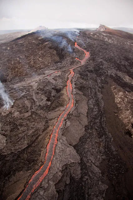 In this September 21, 2011 photo provided by the U.S. Geological Survey, lava flows from Kilauea volcano at Volcanoes National Park in Hawaii. Lava began flowing from the fissure breakout that started last week at Kilauea, a volcano that has been continuously erupting since 1983. It advanced about 2.3 miles before stopping short of the mostly abandoned Royal Gardens subdivision. (Photo by Tim Orr/AP Photo/USGS)