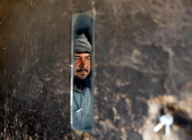 A man is reflected in a mirror as he looks at police officers near the shops during the coronavirus disease (COVID-19) outbreak in Kabul, Afghanistan on April 23, 2020. (Photo by Mohammad Ismail/Reuters)