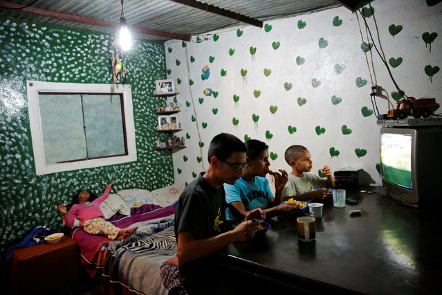 Doris Arocha (C), 30, who was sterilized two months ago, watches television with her children while they eat dinner at their home in San Diego, Venezuela July 19, 2016. (Photo by Carlos Garcia Rawlins/Reuters)