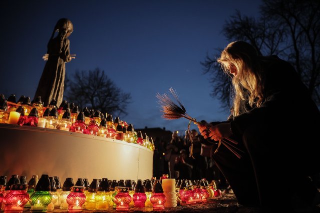 A woman places ears of wheat before the 'Bitter Memory of Childhood' statue by Petro Drozdowsky at the Holodomor Genocide complex of the National Museum in Kyiv, Ukraine, 25 November 2023. The victims of the Holodomor, Ukrainian for 'Death by starvation,' are traditionally commemorated in Ukraine on the last Saturday of November. The Holodomor, or the Great Famine, in the former Soviet era Ukraine claimed millions of lives between 1932 and 1933. (Photo by Oleg Petrasyuk/EPA/EFE)
