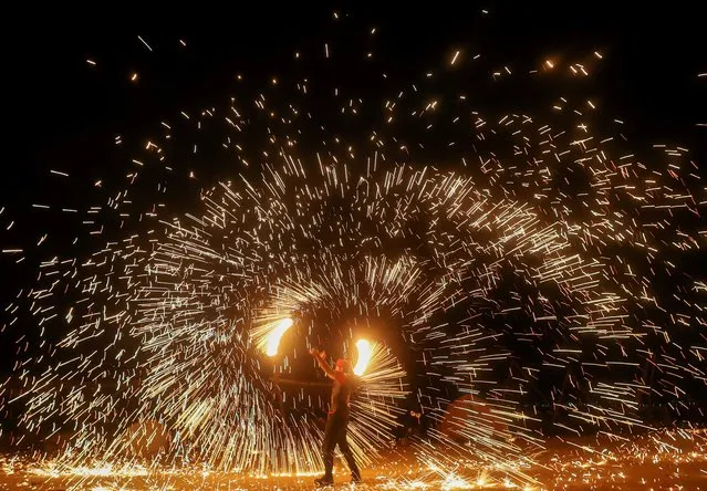 An Egyptian performer plays with fire during a show on Qatrani camp next to Lake Qarun Protectorate in Fayoum, Egypt on September 17, 2022. (Photo by Amr Abdallah Dalsh/Reuters)