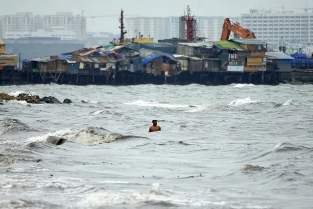 A resident swims along strong waves as Typhoon Noru approaches the seaside slum district of Tondo in Manila, Philippines, Sunday, September 25, 2022. (Photo by Aaron Favila/AP Photo)