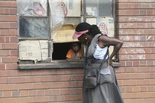 A woman talks to a child through a window in Harare, Thursday May 28, 2020. Manhunts have begun after hundreds of people, some with the coronavirus, fled quarantine centres in Zimbabwe and Malawi while authorities worry they will spread COVID-19 in countries whose health systems can be rapidly overwhelmed. (Photo by Tsvangirayi Mukwazhi/AP Photo)