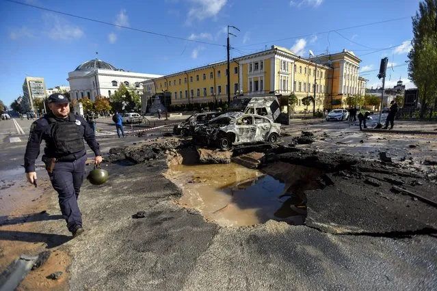 A police officer (L) walks past destroyed cars at a damaged road after shelling in downtown Kyiv (Kiev), Ukraine, 10 October 2022. Explosions have been reported in several districts of the Ukrainian capital Kyiv on 10 October, with rescuers extinguishing fires and helping the victims among the civilian population, the State Emergency Service (SES) of Ukraine said. Russian troops entered Ukraine on 24 February 2022 starting a conflict that has provoked destruction and a humanitarian crisis. (Photo by Oleg Petrasyuk/EPA/EFE/Rex Features/Shutterstock)