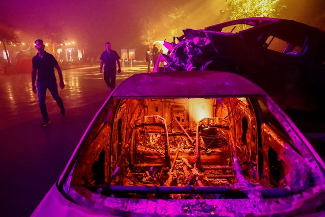 People walk near burnt cars as they view an exhibit that reconstructs the Nova festival grounds and displays the original equipment used at the festival that was attacked by Palestinian Islamist group Hamas from the Gaza Strip on October 7, in Tel Aviv, Israel on December 6, 2023. (Photo by Clodagh Kilcoyne/Reuters)
