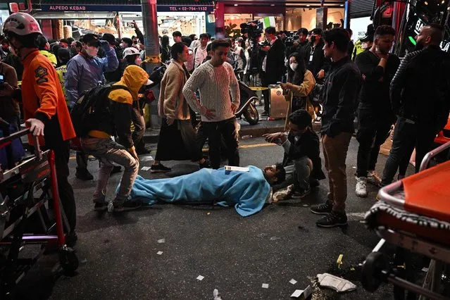 A man receives medical attention, after dozens of people suffered cardiac arrest during Halloween celebrations, in the popular nightlife district of Itaewon in Seoul on October 30, 2022. (Photo by Anthony Wallace/AFP Photo)