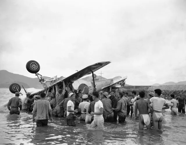 American and South Korean soldiers raise mustang fighter plane in attempt to keep trapped South Korean pilot's head above water after his plane skidded on takeoff van overturned off Yellow Sea Beach in Korea on September 16, 1950. Lt. Chong Yong Chin, American-trained flier, lost his life after receiving honor as first South Korean pilot to be chosen for mission over enemy territory. (Photo by Jim Pringle/AP Photo)