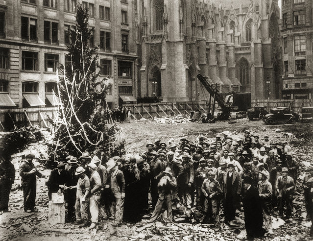 Construction workers line up for pay beside the first Rockefeller Center Christmas tree in New York in 1931.  The Christmas tree went on to become an annual tradition and a New York landmark. St. Patrick's Cathedral is visible in the background on Fifth Avenue. (Photo by AP Photo)