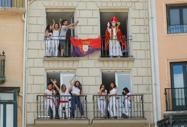 A reveller dressed up as Saint Fermin waves from a balcony in front of the town hall where the firing of “chupinazo”, which opens the San Fermin festival that was cancelled due to the coronavirus disease (COVID-19) outbreak, should have taken place, in Pamplona, Spain on July 6, 2020. (Photo by Jon Nazca/Reuters)